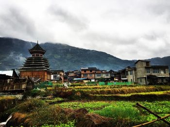 Houses on mountain against cloudy sky