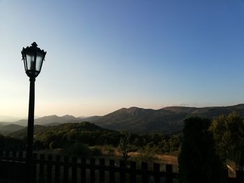 Street light and mountains against clear blue sky