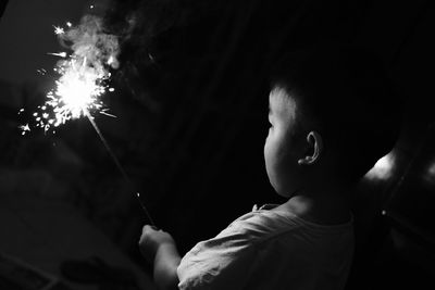 Boy holding lit sparkler at night