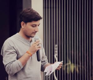 Young man announcing while holding microphone