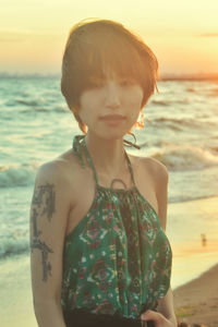 Midsection of woman standing at beach during sunset