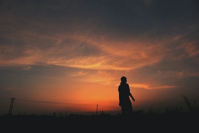 Silhouette person on field against sky during sunset