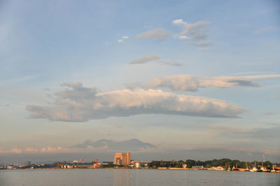 Sea by buildings against sky during sunset