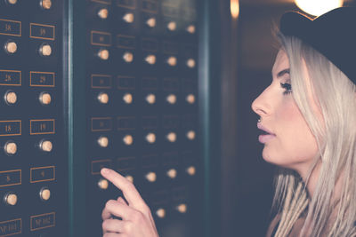 Side view of young woman pushing button