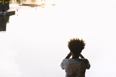 Rear view of woman standing in water against clear sky