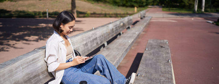 Side view of young woman sitting on bench