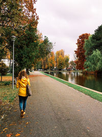 Rear view full length of woman walking on road during autumn