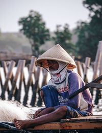 Man holding hat sitting on wood