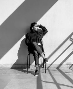 Full length of young man sitting on wall