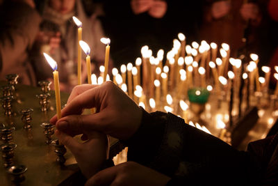 Close-up of hand holding illuminated candles