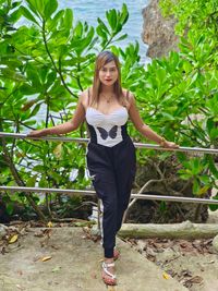 Portrait of young woman standing against plants