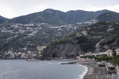 Scenic view of sea by mountains against sky