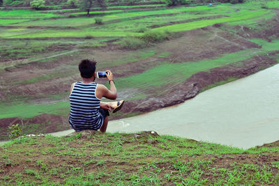 Rear view of man sitting on field