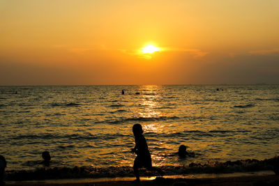 Silhouette people on beach against sky during sunset