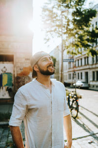 Smiling man standing on street against buildings in city