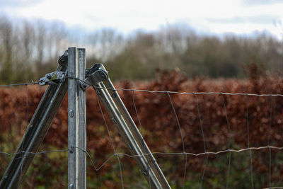 Close-up of barbed wire fence on field