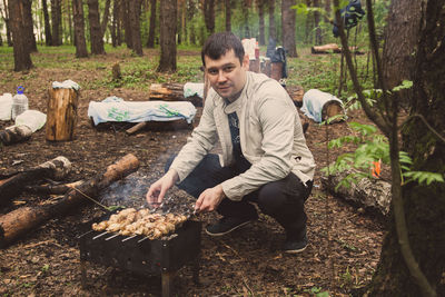 Man preparing food on barbecue grill in forest