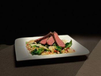 Close-up of salad in plate on table against black background