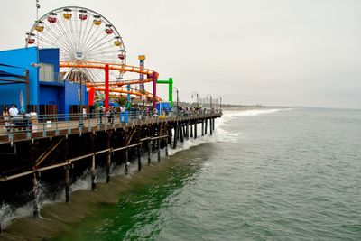 View of ferris wheel by sea against clear sky