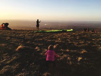 Rear view of baby girl on mountain peak during sunset