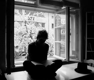 Woman reading book on table at home