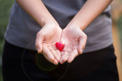 Midsection of woman holding red heart shape