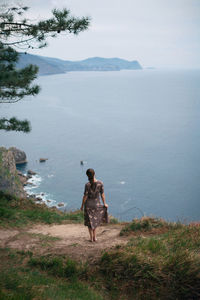 Rear view of women on mountain by sea