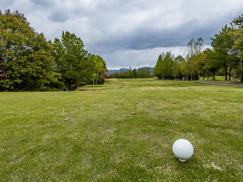 View of golf ball on grassy field against cloudy sky