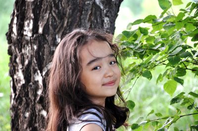 Portrait of smiling girl by tree