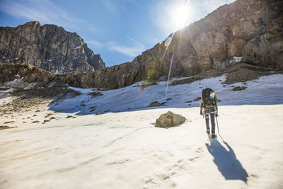 Rear view of backpacker approaching rocky cliff.