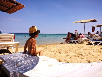 People relaxing on beach against sky