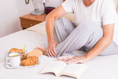 Midsection of man sitting on table at home