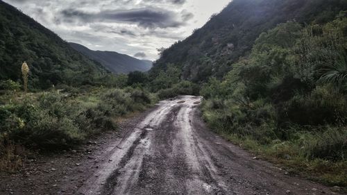 Empty dirt road leading towards mountains