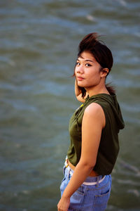 Portrait of young woman standing against lake