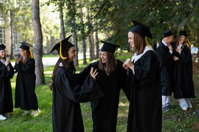Rear view of woman wearing graduation gown standing in forest