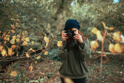 Woman photographing in forest