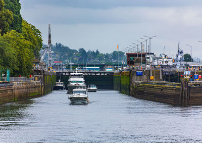 Sailboats moored on river in city against sky