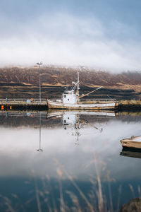 Scenic view of fishing boat with reflection on the water against sky
