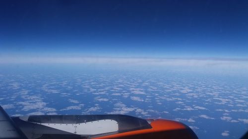 Airplane flying over sea against blue sky
