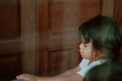 Side view of young woman looking through window