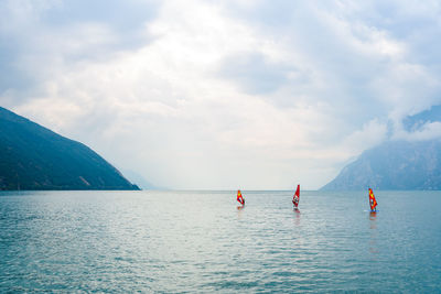 Rear view of people on sea against sky