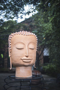 Close-up of buddha statue against trees