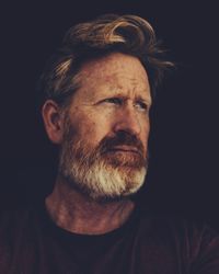 Close-up portrait of man against black background