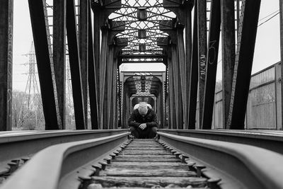 Person sitting on railroad tracks