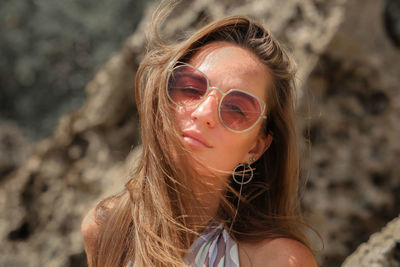 Close-up portrait of young woman wearing sunglasses outdoors