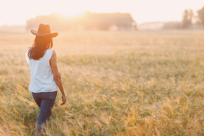 Rear view of woman standing on grassy field