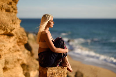 Side view of young woman with eyes closed sitting at beach