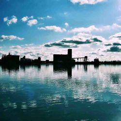 Silhouette built structure in water against sky