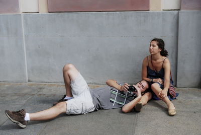 Full length of couple relaxing against wall