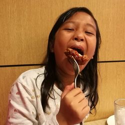 Girl eating fried chicken at restaurant
